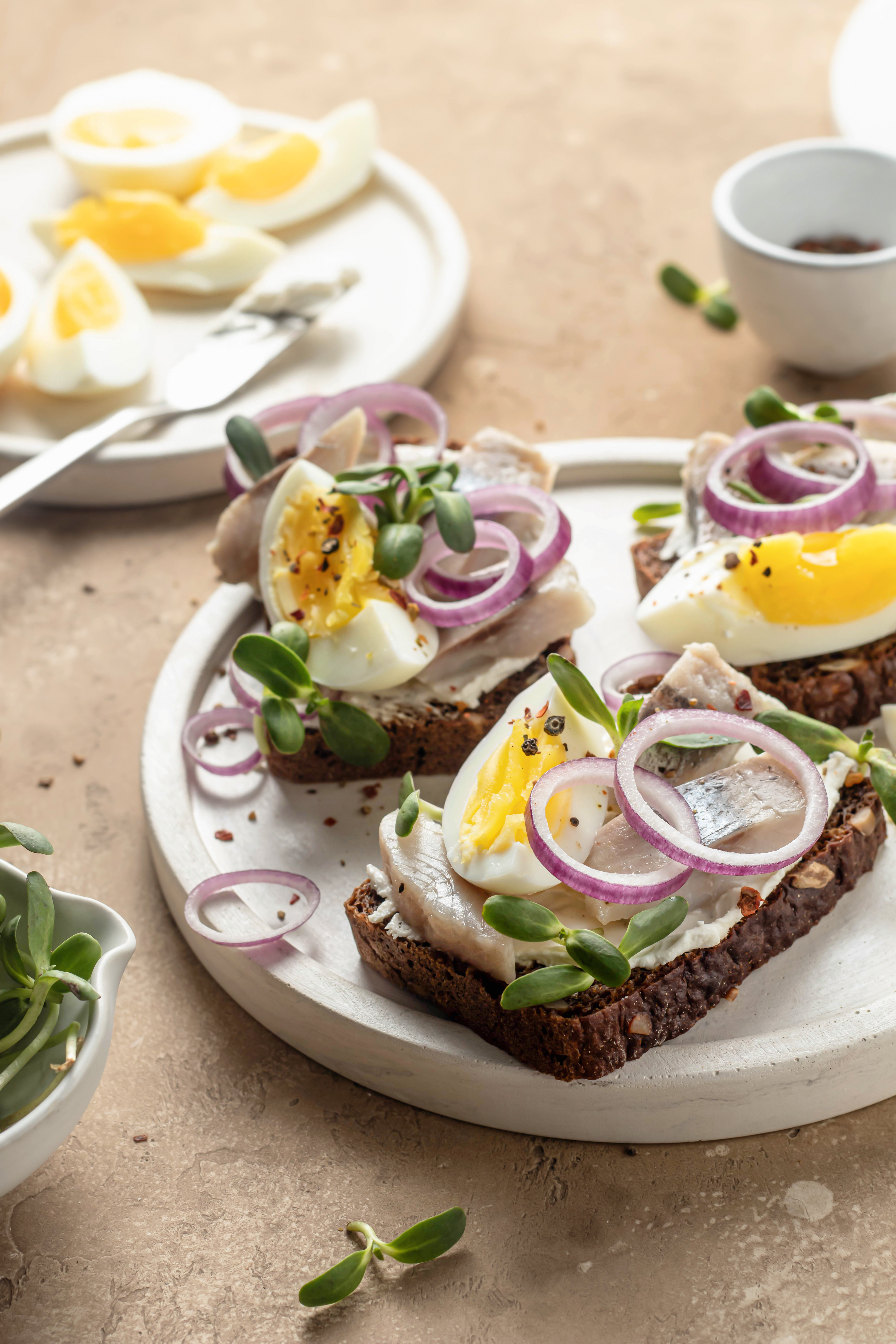 En sildemad med sild på rugbrød, toppet med skiveskåret hårdkogt æg og løg.
